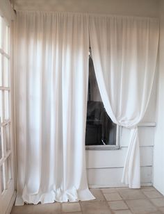 an open window with white drapes in front of it and a tiled floor next to it