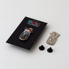 a pair of black earbuds sitting next to a clipboard with an animal pin on it