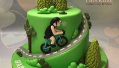 a green cake with a woman riding a bike on the front and trees on the back