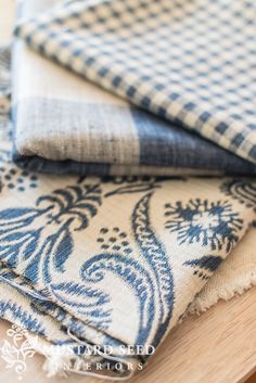 two blue and white cloths sitting on top of a wooden table next to each other