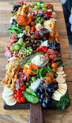 a long wooden platter filled with lots of different types of fruit and veggies