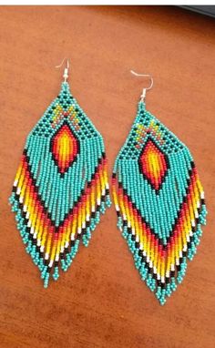 a pair of colorful beaded earrings sitting on top of a wooden table