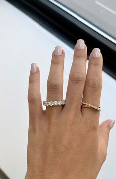 a woman's hand with two rings on her fingers and one ring in the middle