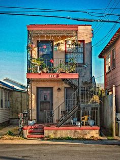 an apartment building with plants on the balcony and stairs leading up to the second floor