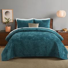 a bed in a bedroom with blue comforter and pillows