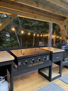 an outdoor bbq with lights strung from the ceiling and wood flooring on it