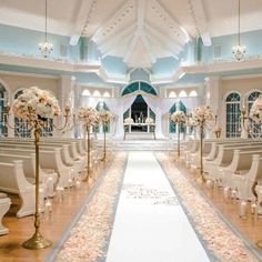 the aisle is decorated with white flowers and gold candelabras for an elegant wedding