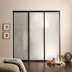 a bedroom with sliding glass doors on the wall and wood flooring in front of it