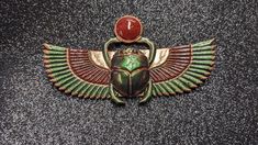 an egyptian scarp with a red stone on it's head and two wings