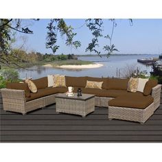 an outdoor sectional sofa set with pillows on the top and bottom, sitting on a wooden deck