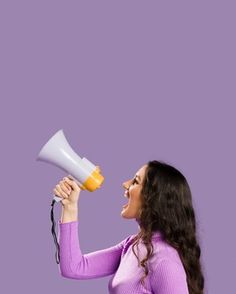 a woman holding a yellow and white megaphone in her right hand while yelling into it