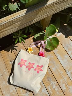 a white bag sitting on top of a wooden floor next to flowers and plants in a pot