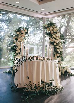 a table with flowers and candles on it in front of a window at a wedding