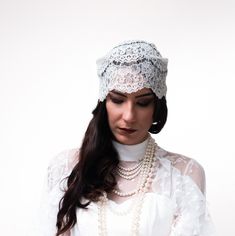 a woman wearing a white lace headband and pearls