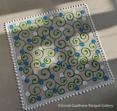 a white table cloth with blue and green designs on it, sitting on a tile floor