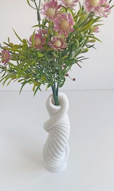 a white vase with pink flowers in it