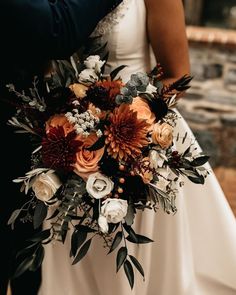 the bride and groom are holding each other close to one another with their wedding bouquet in front of them