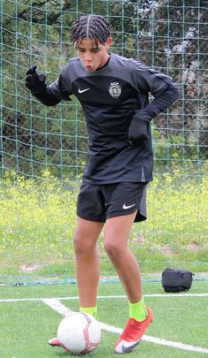 a young man kicking a soccer ball on top of a field