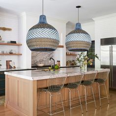 a kitchen with two hanging lights over the island and four chairs in front of it