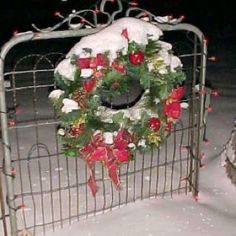 a christmas wreath on a gate in the snow