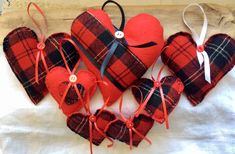 red and black plaid heart ornaments are arranged on a white cloth sheet with twine ribbons