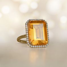 This stunning ring features an emerald-cut 11.35-carat citrine with beautiful saturation. The center stone is surrounded by a halo of diamonds. This ring is 18k yellow gold and decorated with a floral-motif openwork under-gallery.  ✦ GEMSTONE SPECIFICATIONS:    Center Gemstone: Citrine  Gemstone Cut: Emerald Cut  Gemstone Weight: Approx 11.35 Carats  ✦  RING SPECIFICATIONS:    Material: 18k Yellow Gold  Stones: Citrine and Diamond      ✦ WHAT COMES IN YOUR SHIPMENT:    - Your Ring  - Quality Rin Luxury Emerald Cut Gemstone Halo Ring, Luxury Citrine Topaz Ring With Emerald Cut, Luxury Citrine Emerald Cut Rings, Luxury Citrine Ring Emerald Cut, Elegant Orange Emerald Cut Jewelry, Luxury Citrine Rings With Halo Setting, Elegant Citrine Topaz Ring With Halo Setting, Formal Citrine Topaz Ring With Halo Setting, Luxury Topaz Ring With Halo Design For Formal Occasions