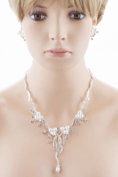 Elegant and exquisite, this silver-plated necklace and earring set features white faux pearls, clear crystal rhinestones in a stunning floral vine design. The floral design of this bridal set makes it an enchanting choice for your wedding. This set coordinates beautifully with your white or ivory dress. This lovely jewelry set sparkles with elegant beauty. This accessory would make a beautiful addition for weddings, proms, homecomings or any formal affair! The necklace has a lobster claw closure Silver Pearl Bridal Sets For Formal Occasions, Formal Silver Pearl Bridal Sets, Silver Pearl Embellished Jewelry Sets For Wedding, Silver Pearl Wedding Jewelry Sets, Elegant Silver Pearl Jewelry Sets, Silver Pearl Necklace With Rhinestones For Wedding, Silver Crystal Jewelry Set With Pearl Drop, Silver Pearl Rhinestone Necklace For Formal Occasions, Formal Silver Rhinestone Necklace With Pearls