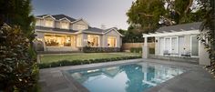 a house with a pool in front of it and landscaping around the back yard area