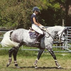 a woman riding on the back of a white horse