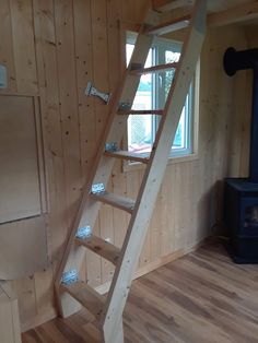 there is a ladder in the corner of this room with wood flooring and wooden walls