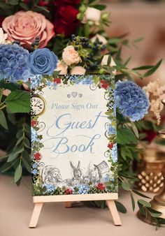 a sign that says guest book with flowers and greenery in front of the sign