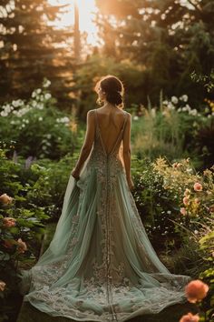 a woman standing in the middle of flowers with her back to the camera, wearing a dress