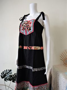 Pretty True Vintage midi sundress from the early 1980s. Empire waist, A-line skirt, adjustable straps, tie bands in the front, cute intarsia bib, floral trims (big flowers and ditsy florals). Zipper in the back, unlined. Perfect for a summer vacation! Looks great with a pair of sandals or clogs and combined with a wicker bag. ERA: 1980s BRAND: No brand label anymore COLOR: Black, pink, red, orange, green, lilac, white, mustard FABRIC; No fabric tag, probably pure cotton SIZE: No size tag, fits b Cotton Sundress With Knotted Straps, Summer Cotton Suspender Dress With Straps, Summer Cotton Suspender Dress, Sleeveless Cotton Sundress With Straps, Cotton Sleeveless Suspender Dress With Straps, Cotton Sleeveless Suspender Dress, Cotton Sundress With Tie Fastening For Summer, Cotton Suspender Dress Sleeveless, Cotton Suspender Dress With Straps