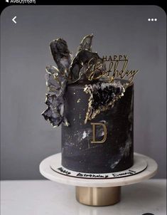 a black and gold birthday cake with flowers on top