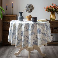 a table topped with a vase filled with flowers and two candles sitting on top of it