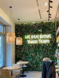 the inside of a restaurant with plants growing on the wall and tables in front of it