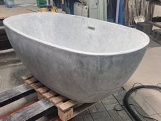 a large concrete bowl sitting on top of a wooden pallet