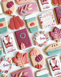 many decorated cookies are arranged on a white surface with autumn leaves and pumpkins in the background