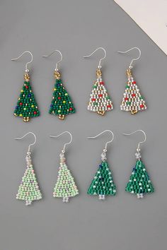 six pairs of beaded christmas tree earrings in various colors and sizes on a gray surface