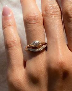 a woman's hand with a gold and white diamond ring on top of it