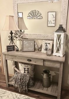 a wooden table topped with a mirror next to a lamp and other decor on top of a hard wood floor