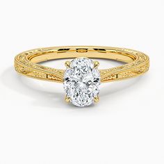 a yellow gold engagement ring with a oval cut diamond in the center and filigree band