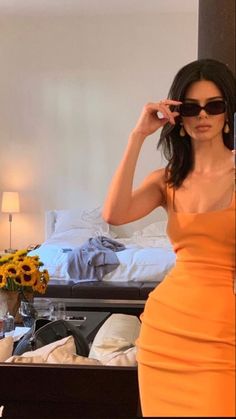 a woman in an orange dress taking a selfie