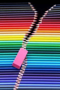 colored pencils with eraser stuck in between them on a black background, the image appears to have been altered