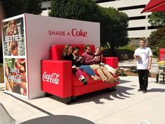 some people are sitting on a coca cola couch