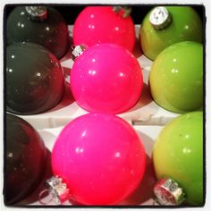 there are many different colored balls in the box with bows on each one, and they look like christmas ornaments