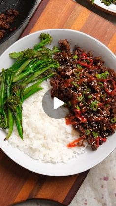 a white bowl filled with rice and broccoli on top of a wooden cutting board