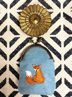 a coin purse with a fox on it and a gold sunburst hanging from the side