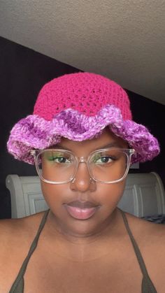 a woman wearing glasses and a pink crocheted hat with purple flowers on it