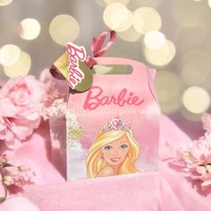 a pink bag with a barbie doll on it and flowers in front of the package